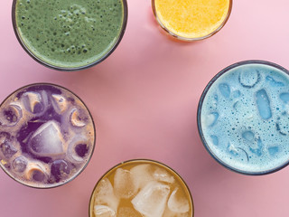 Glasses with colorful summer drinks, cocktails, vegetable strips, coffee drinks and orange juice, top photo, pink background. Concept for restaurant or bar