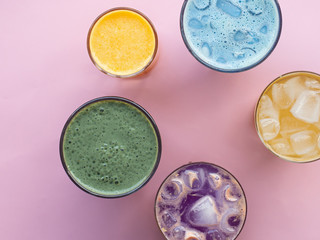 Glasses with colorful summer drinks, cocktails, vegetable strips, coffee drinks and orange juice, top photo, pink background. Concept for restaurant or bar