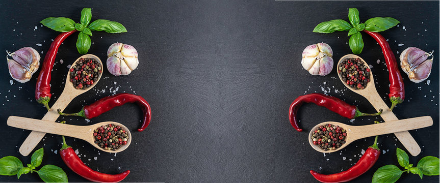 Long wide banner with fresh aromatic basil, peppercorns mix, hot chili pepper, sea salt and garlic on black textured background. Restaurant menu template. Copy space for your text.