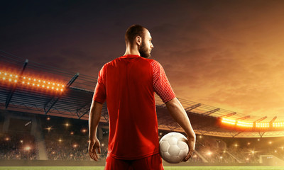 Professional soccer player on a night soccer stadium with cheering fans. Dramatic night sky