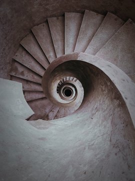 A spiral stone staircas going down.