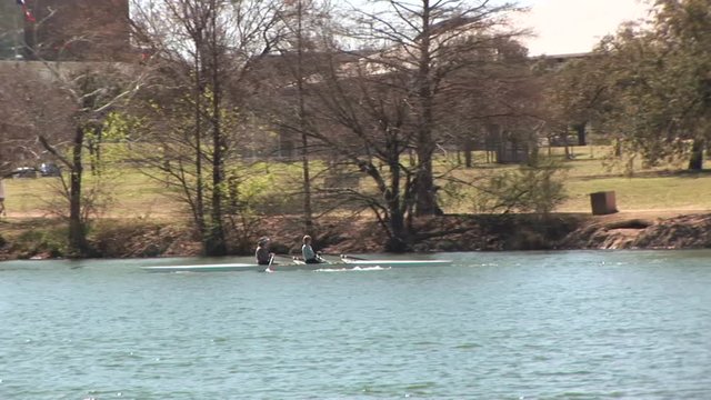 camera follows two people rowing a small boat