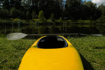 yellow slalom boat with an oar stands on the bank of the river with a gate for slalom
