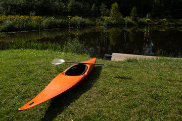orange slalom boat with an oar stands on the bank of the river with a gate for slalom