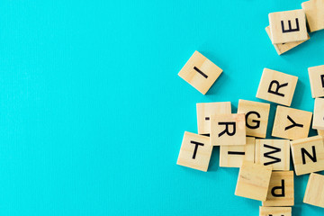 Pile of wooden letters on the surface of a blue background, selective focus