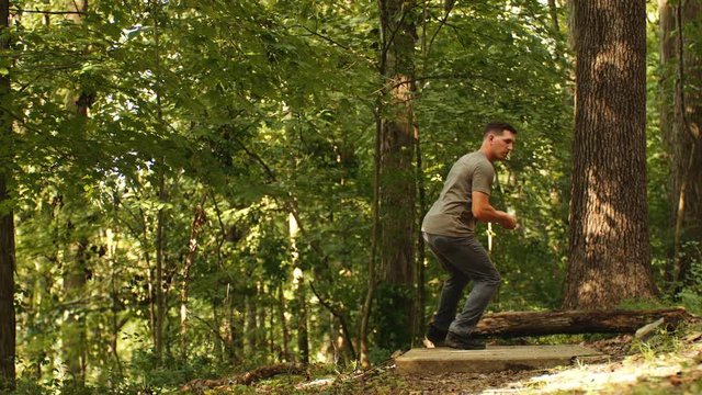 Man drives disc golf disc, long shot, towards camera, slow motion