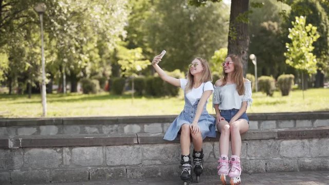 Two cute girls rollerblading and taking Selfies