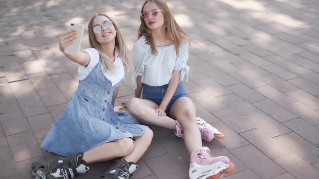 Girls in rollerblades taking a selfie while sitting down
