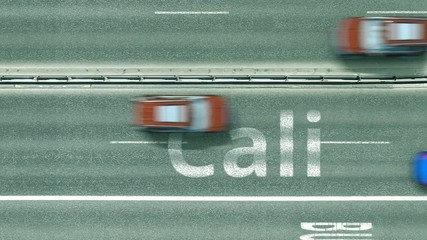 Aerial top down view of the road with cars revealing Cali caption. Car travel in Colombia conceptual clip