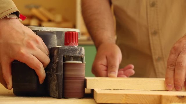 Wood workers work with a wood grinder and polished small wooden frame