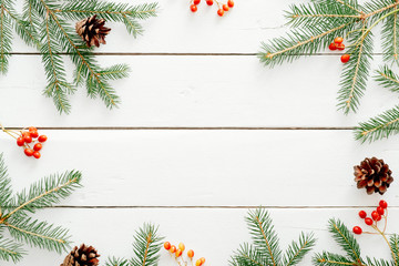 Fototapeta na wymiar Christmas composition. Christmas fir tree branches, red berry, pine cones on wooden white rustic background. Flat lay, top view. Copy space. Banner template