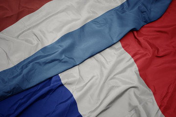 waving colorful flag of france and national flag of luxembourg.