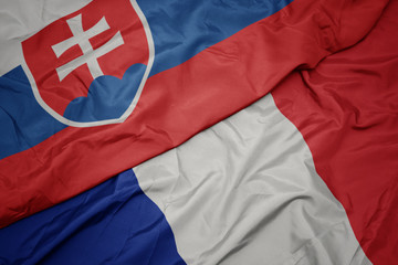 waving colorful flag of france and national flag of slovakia.