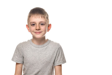 Portrait of a smiling boy in a gray t-shirt. Schoolboy. White background, place for text.
