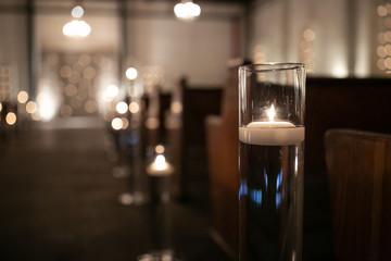 candles in aisle at wedding with benches