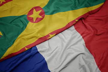 waving colorful flag of france and national flag of grenada.