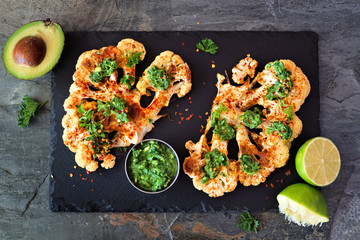 Cauliflower steaks with a cilantro lime sauce. Above view on a slate platter. Healthy eating, plant...