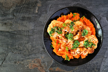 Cauliflower steak with sweet potato mash. Top view on a dark stone background. Healthy eating, plant based meat substitute concept.