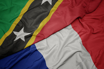 waving colorful flag of france and national flag of saint kitts and nevis.