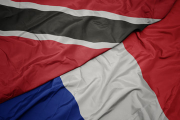 waving colorful flag of france and national flag of trinidad and tobago.