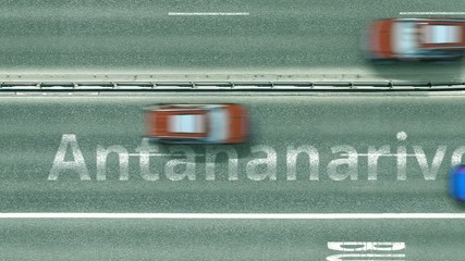 Aerial top down view of the road with cars revealing Antananarivo caption. Car travel in Madagascar conceptual clip