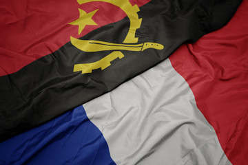 waving colorful flag of france and national flag of angola.