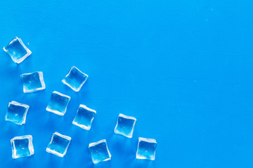 Pile of ice cubes on blue bar desk background top view mock up