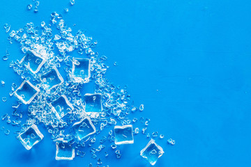 Pile of ice cubes on blue bar desk background top view mock up