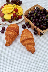 Fruit salad with fresh sweet cherry, mango and croissants on the table  white background. Flat lay, concept composition brackfast