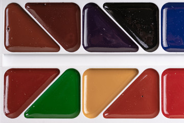 A palette of multi-colored watercolor paints in a school set.