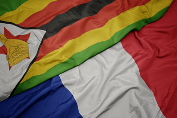 waving colorful flag of france and national flag of zimbabwe.