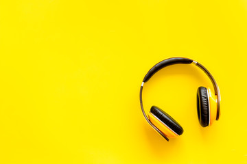 Wireless headphones as music gadgets on yellow background top view mock-up