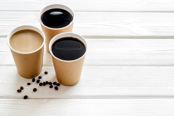 Beans, black coffee and coffee with milk to-go on white wooden background space for text