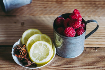 Framboises fraichement cueillies dans un pot en métal et tranches de citron