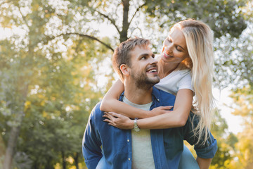 Fototapeta premium Low angle view of young beautiful couple piggybacking and having fun outdoors