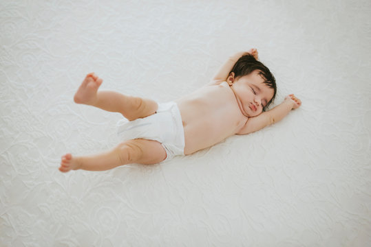 adorable baby girl stretching in bed while sleeping