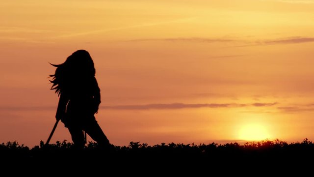 silhouette of Important leader of Indians walking with spear at sunset.