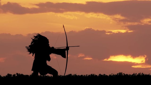 silhouette of Native American shoots from a bow at sunset. Native American shoots from a bow while hunting.