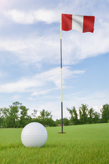 Peru flag on golf course putting green with a ball near the hole