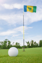 Obraz premium Saint Vincent and the Grenadines flag on golf course putting green with a ball near the hole