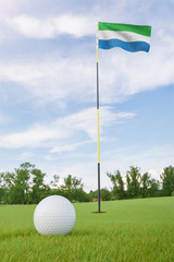 Obraz premium Sierra Leone flag on golf course putting green with a ball near the hole