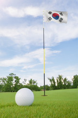 Obraz premium South Korea flag on golf course putting green with a ball near the hole