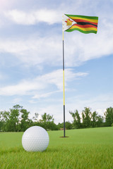 Obraz premium Zimbabwe flag on golf course putting green with a ball near the hole