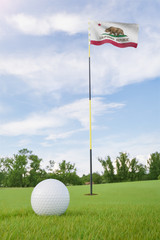 Obraz premium California flag on golf course putting green with a ball near the hole