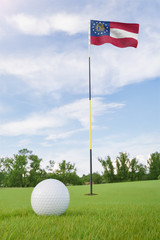 Obraz premium Georgia flag on golf course putting green with a ball near the hole