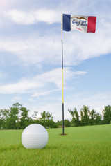Obraz premium Iowa flag on golf course putting green with a ball near the hole