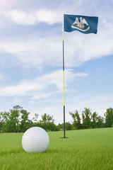 Obraz premium Louisiana flag on golf course putting green with a ball near the hole