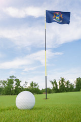 Obraz premium Michigan flag on golf course putting green with a ball near the hole