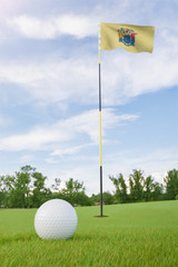 Obraz premium New Jersey flag on golf course putting green with a ball near the hole