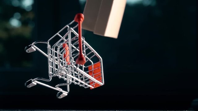 Slow motion shot of shopping cart with box falling down. Retail problems or accident related conceptual clip